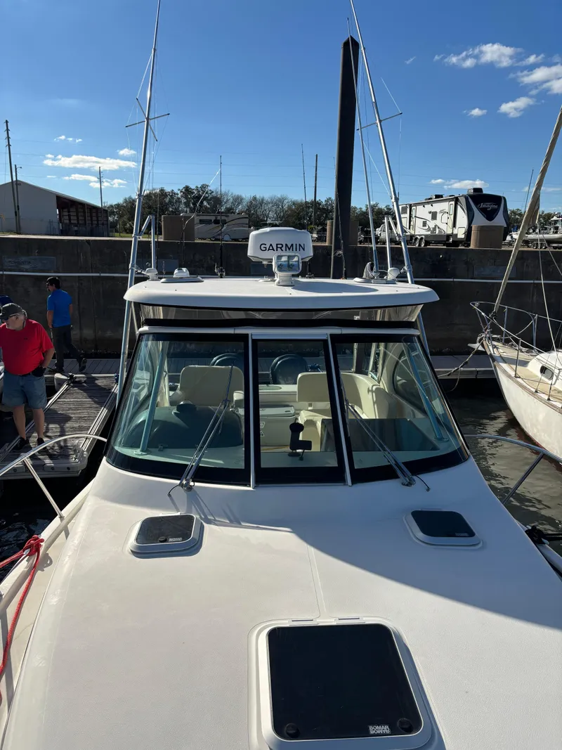 Slide: The Image of 2006 Pursuit 3370 Offshore boat docked, featuring Garmin equipment under a clear blue sky. - 3
