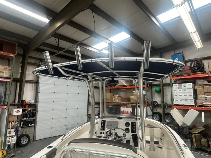Slide: The Image of 2019 Robalo R222 Center Console boat in a garage, showcasing helm and T-top. - 17