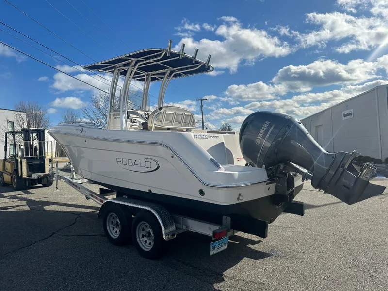 Slide: The Image of 2019 Robalo R222 Center Console boat on trailer, parked outdoors under a blue sky. - 2