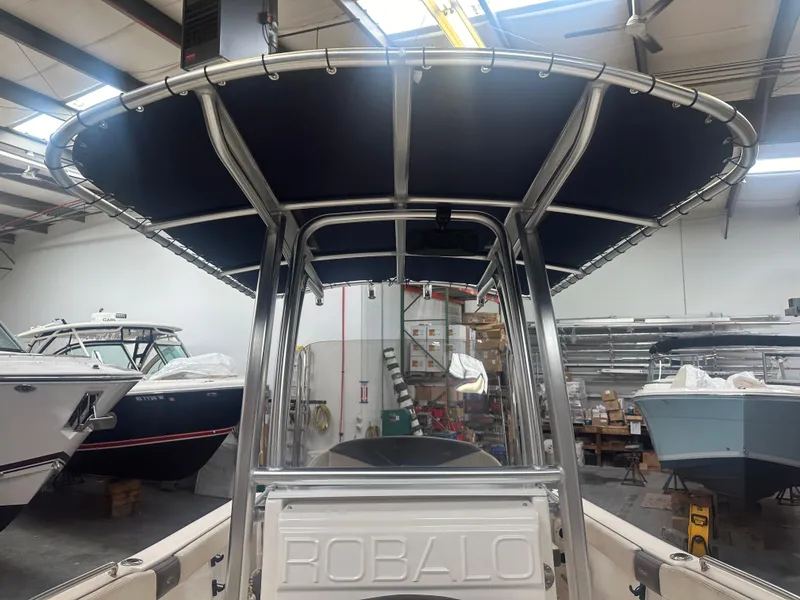 Slide: The Image of 2019 Robalo R222 Center Console boat in a showroom, featuring a sturdy T-top. - 7