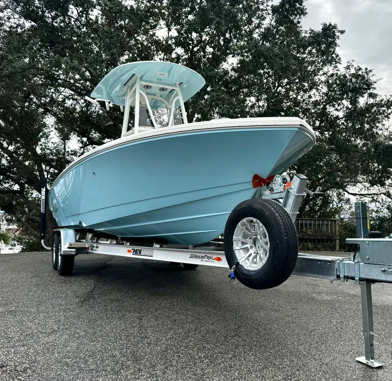 Slide: The Image of 2025 Pathfinder 2400TRS boat on trailer, parked outdoors, with trees in the background. - 2