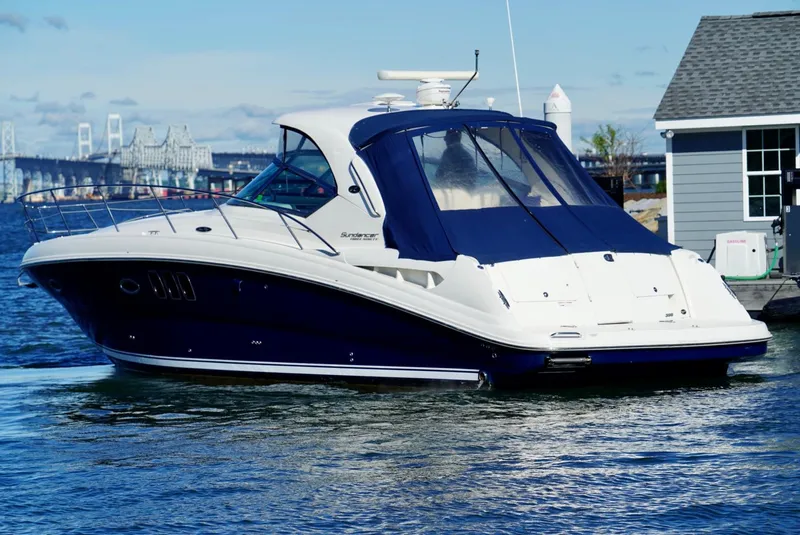 Slide: The Image of 2010 Sea Ray 390 Sundancer yacht docked near a marina with a bridge in the background. - 12