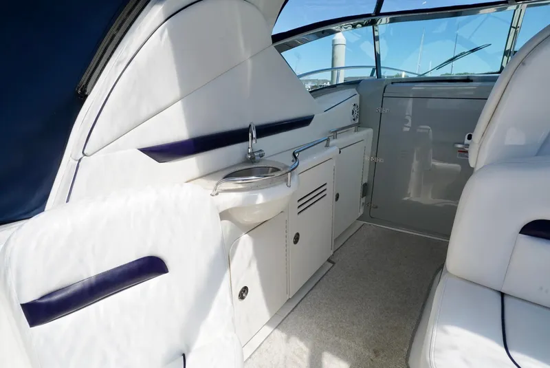Slide: The Image of Interior view of 2010 Sea Ray 390 Sundancer yacht, featuring sleek white seating and compact kitchenette. - 21
