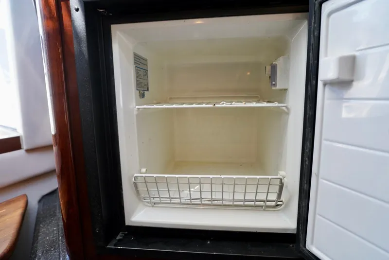 Slide: The Image of Empty refrigerator inside 2010 Sea Ray 390 Sundancer yacht, featuring wire shelf and basket. - 32