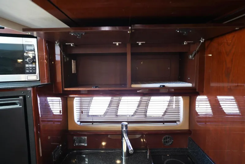 Slide: The Image of Interior of 2010 Sea Ray 390 Sundancer kitchen with open cabinets and modern appliances. - 34