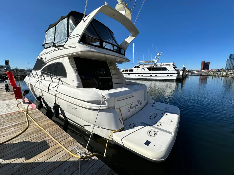 Slide: The Image of 1999 Cruisers 5000 Sedan Sport yacht docked at marina under clear blue sky. - 1