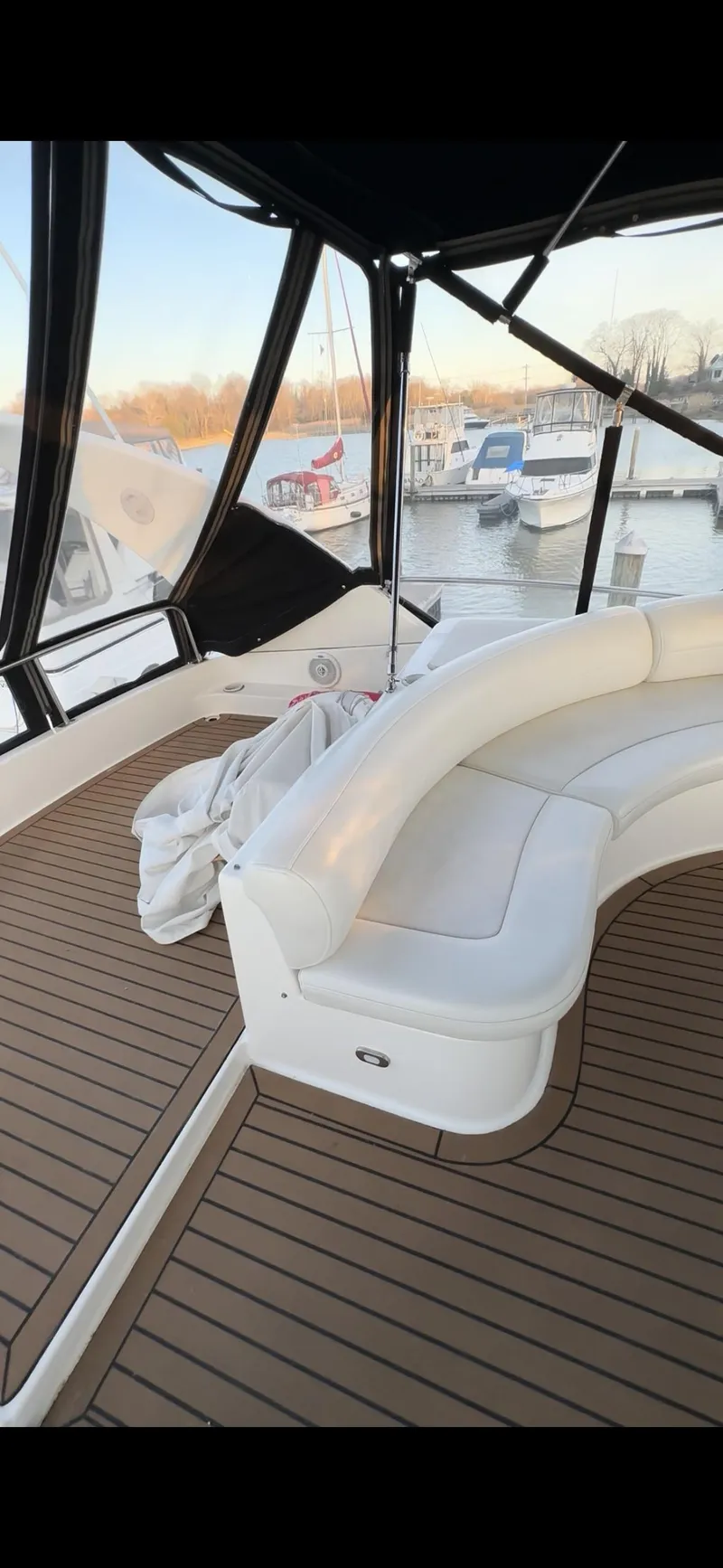 Slide: The Image of 1999 Cruisers 5000 Sedan Sport yacht with white seating and wooden deck in a marina. - 17