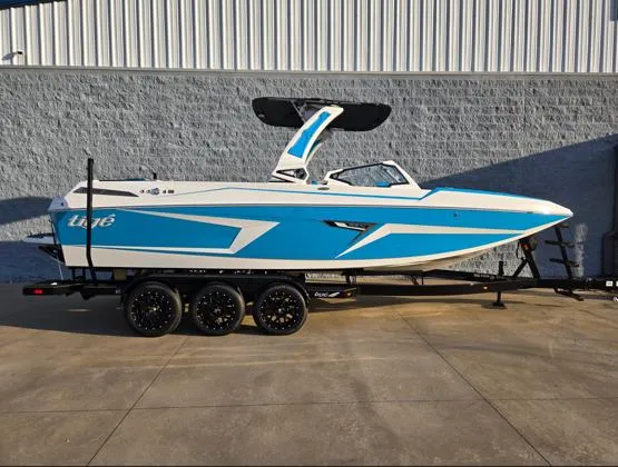 The Image of 2025 Tigé 24RZX boat on trailer, blue and white design, parked outdoors. - 1