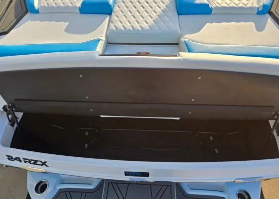 Slide: The Image of 2025 Tigé 24RZX boat interior with open storage compartment and blue seating. - 15