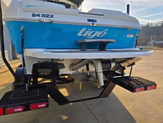 Slide: The Image of 2025 Tigé 24RZX boat rear view with blue hull and trailer. - 16