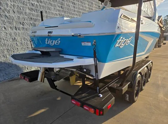 Slide: The Image of 2025 Tigé 24RZX boat on trailer, blue and white design, parked outdoors. - 17