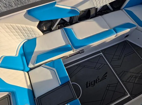 Slide: The Image of 2025 Tigé 24RZX boat interior with blue and white seating and branded flooring. - 6