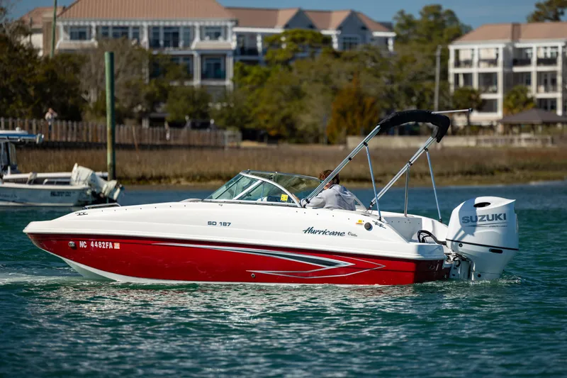 Slide: The Image of 2023 Hurricane SunDeck 187 OB boat cruising on a sunny day near waterfront buildings. - 7