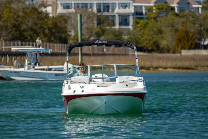 Slide: The Image of 2023 Hurricane SunDeck 187 OB boat cruising on a scenic waterway. - 9
