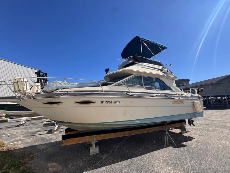 The Image of 1988 Sea Ray 265 Sedan Bridge boat on dry dock under clear blue sky. - 0