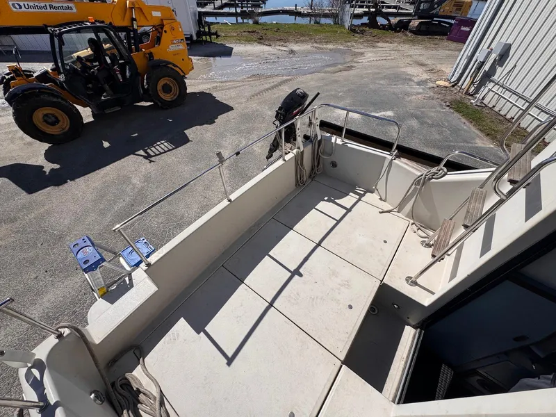 Slide: The Image of 1988 Sea Ray 265 Sedan Bridge boat deck in a marina with equipment nearby. - 11