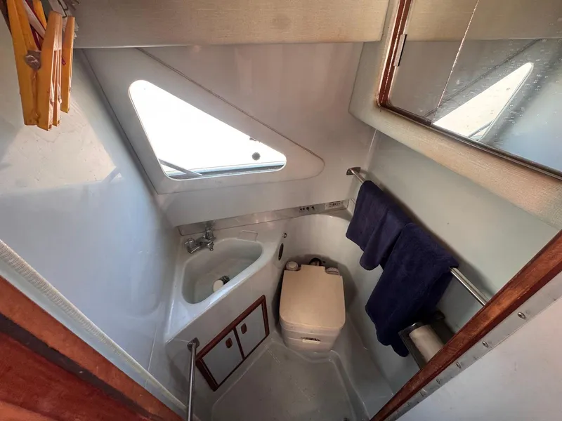 Slide: The Image of Compact bathroom in 1988 Sea Ray 265 Sedan Bridge boat, featuring sink, toilet, and mirror. - 16