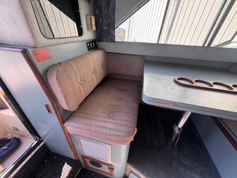 Slide: The Image of Interior of 1988 Sea Ray 265 Sedan Bridge with cushioned seating and table. - 18