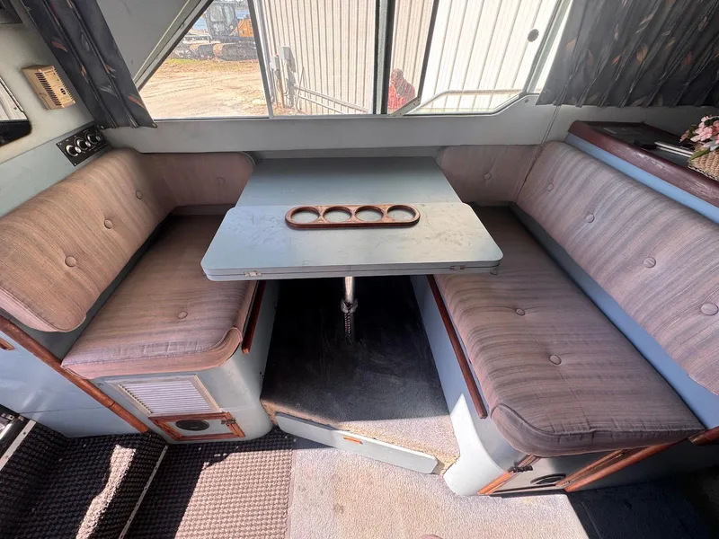 Slide: The Image of 1988 Sea Ray 265 Sedan Bridge interior with dining area and cushioned seating. - 20