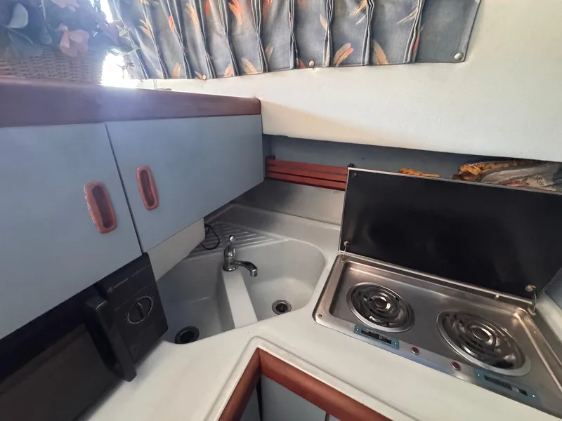 Slide: The Image of 1988 Sea Ray 265 Sedan Bridge kitchen with stove, sink, and cabinets. - 24