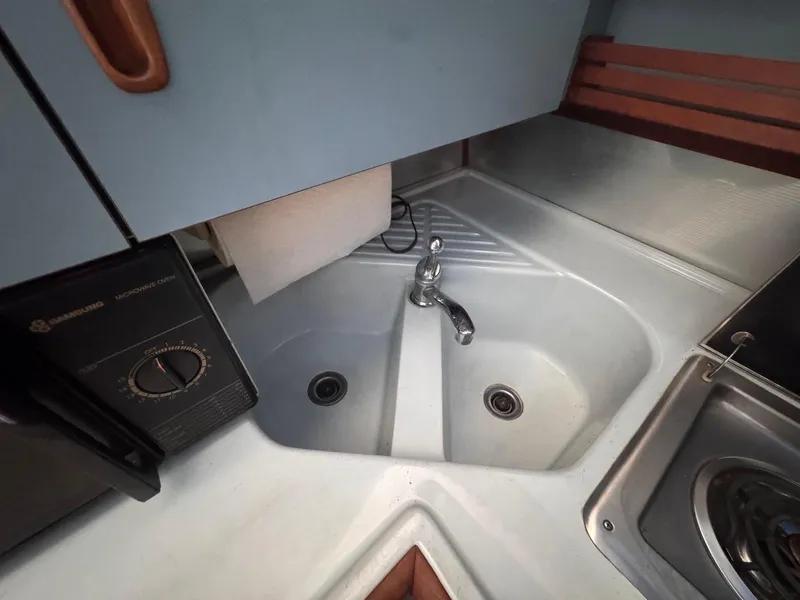 Slide: The Image of 1987 Sea Ray 265 Sedan Bridge kitchen sink with faucet and stove. - 25