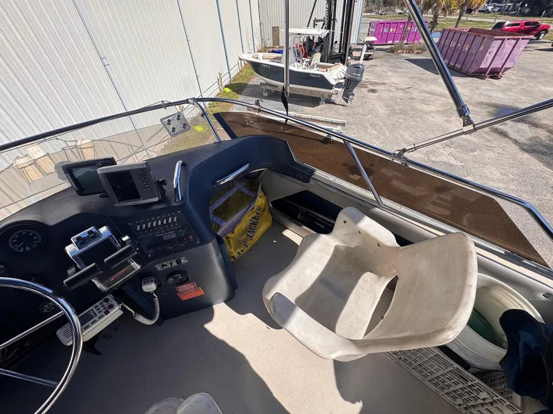 Slide: The Image of 1988 Sea Ray 265 Sedan Bridge helm with controls and seating, docked outdoors. - 37