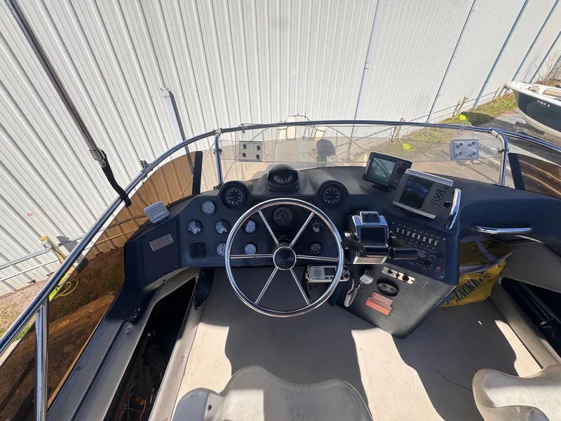 Slide: The Image of 1988 Sea Ray 265 Sedan Bridge helm with steering wheel and navigation instruments. - 45
