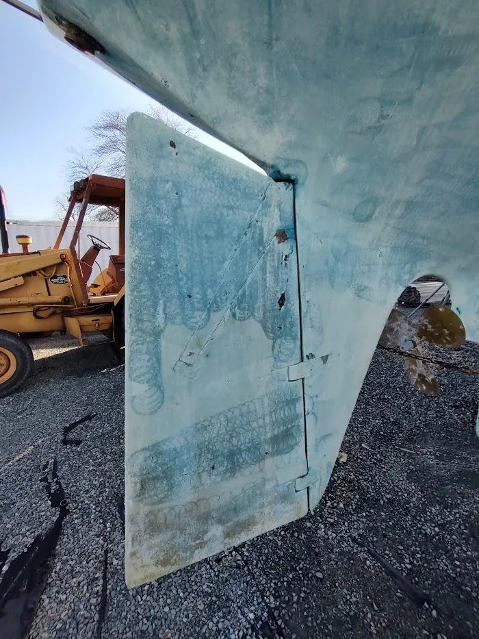 Slide: The Image of 1977 Hallberg-Rassy 41 sailboat rudder with visible wear, parked on gravel. - 11