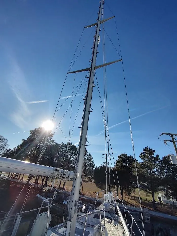 Slide: The Image of Sailboat mast of 1977 Hallberg-Rassy 41 under clear blue sky with sun and trees. - 13