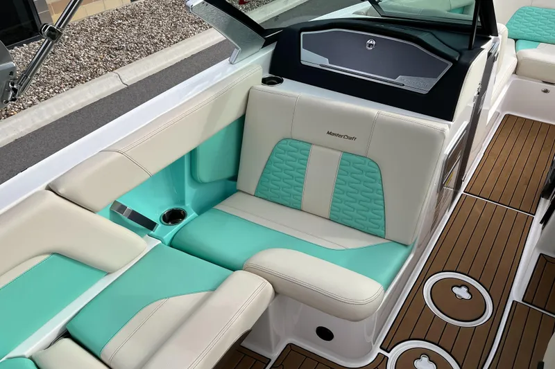 Slide: The Image of 2022 MasterCraft X24 boat interior with teal and beige seating, featuring modern design and wood accents. - 11