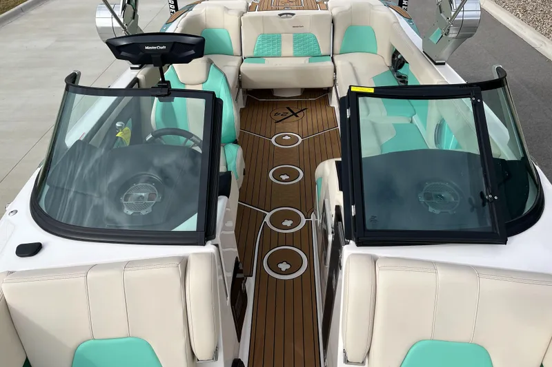 Slide: The Image of 2022 MasterCraft X24 boat interior with teal and white seating, wooden flooring. - 13