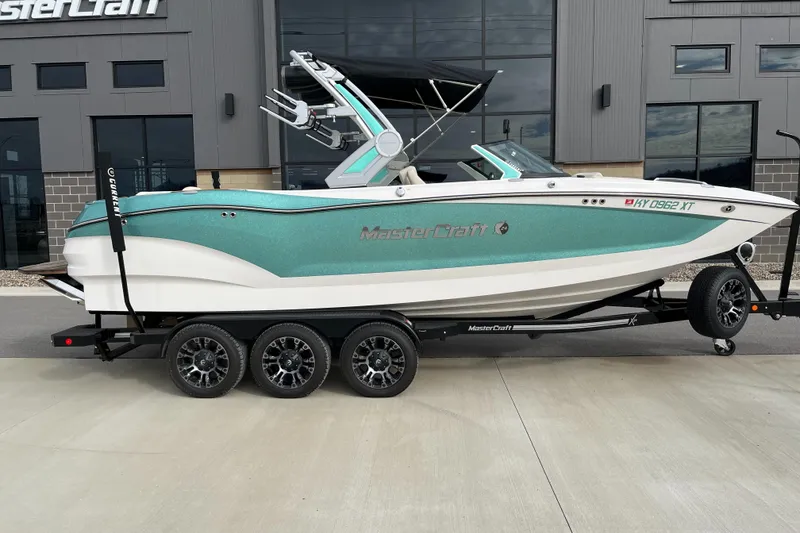 Slide: The Image of 2022 MasterCraft X24 boat on trailer, parked outside a building. - 2