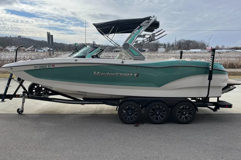 Slide: The Image of 2022 MasterCraft X24 boat on trailer, side view, teal and white design. - 5