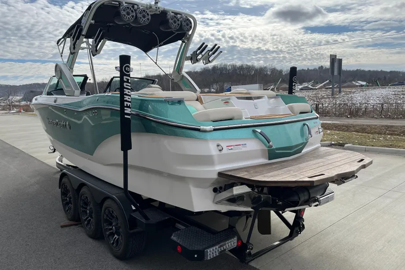 Slide: The Image of 2022 MasterCraft X24 boat on trailer, teal and white design, parked outdoors. - 6