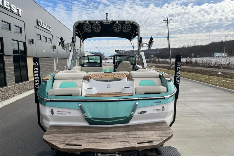 Slide: The Image of 2022 MasterCraft X24 boat with teal accents parked outdoors. - 8