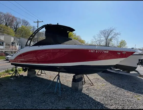 Slide: The Image of 2021 Chaparral 23 SSi boat in red and white, elevated on stands outdoors. - 1