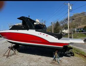 Slide: The Image of 2021 Chaparral 23 SSi boat with red and white exterior on a stand outdoors. - 2
