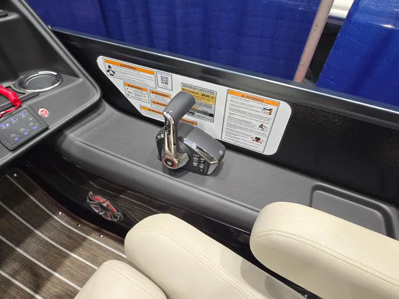 Slide: The Image of 2025 Premier Intrigue boat throttle control with safety instructions and beige seating. - 26