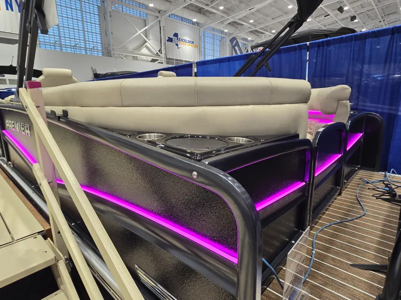 Slide: The Image of 2025 Premier Intrigue boat with pink LED lights and beige seating at a boat show. - 3