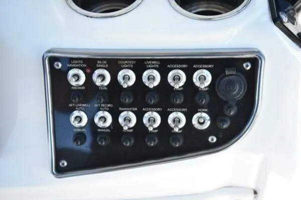 Slide: The Image of Control panel of a 2022 NauticStar 2302 Legacy boat with various switches and controls. - 11