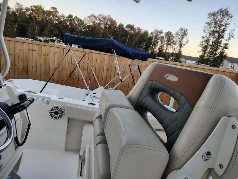 Slide: The Image of 2020 Cobia 240 Center Console boat interior with seating and steering wheel, outdoors. - 7