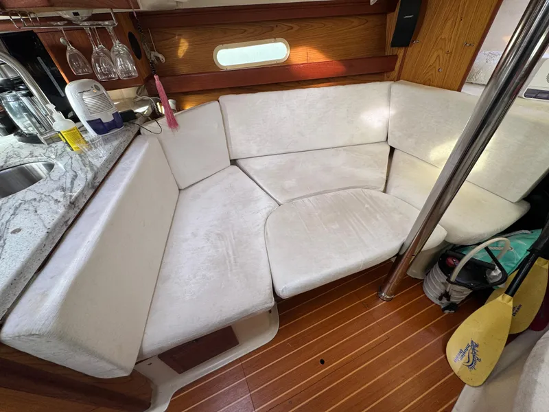Slide: The Image of Interior of a 2000 Hunter 340 sailboat with white cushioned seating and wooden flooring. - 6
