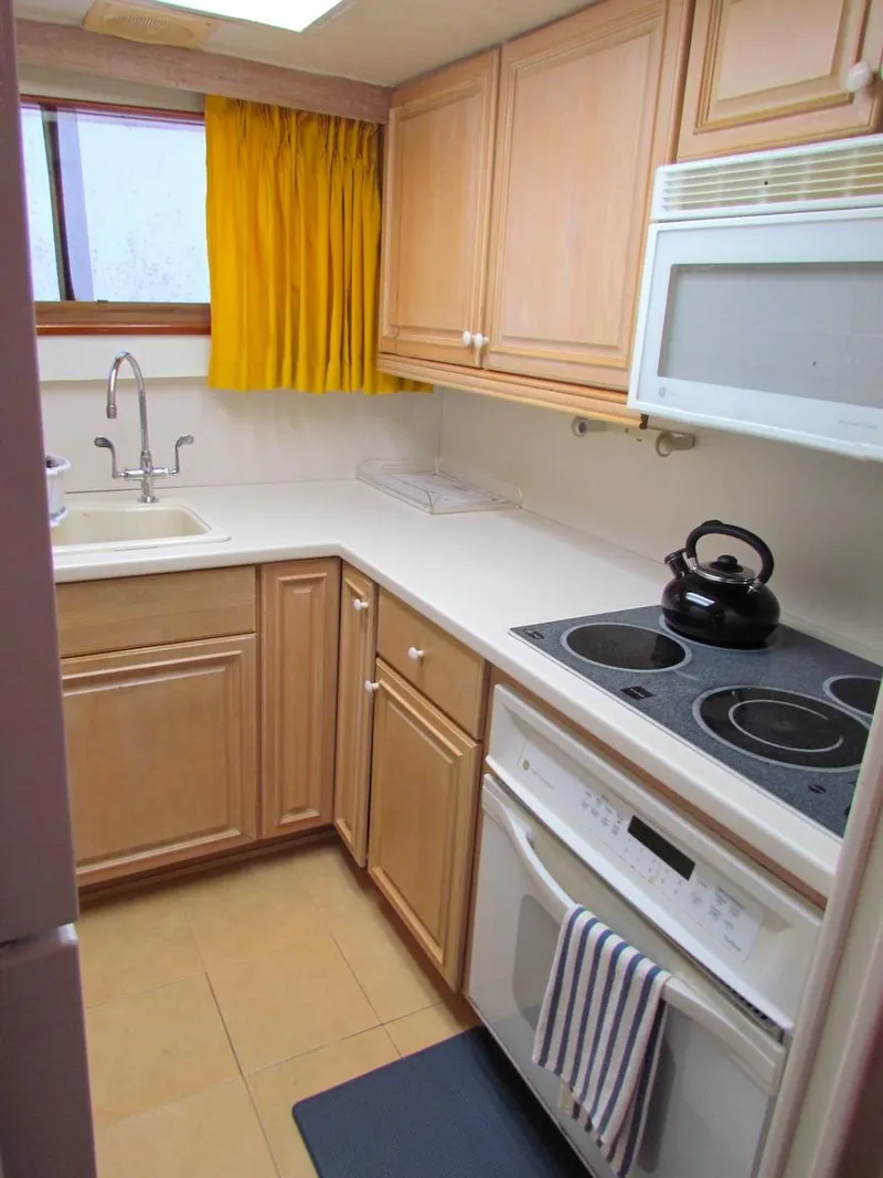 Slide: The Image of 1972 Hargrave 67 Motor Yacht kitchen with wooden cabinets, stove, and yellow curtains. - 23