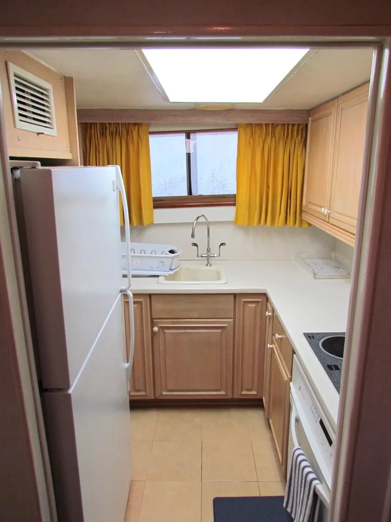 Slide: The Image of 1972 Hargrave 67 Motor Yacht kitchen with wooden cabinets and yellow curtains. - 24