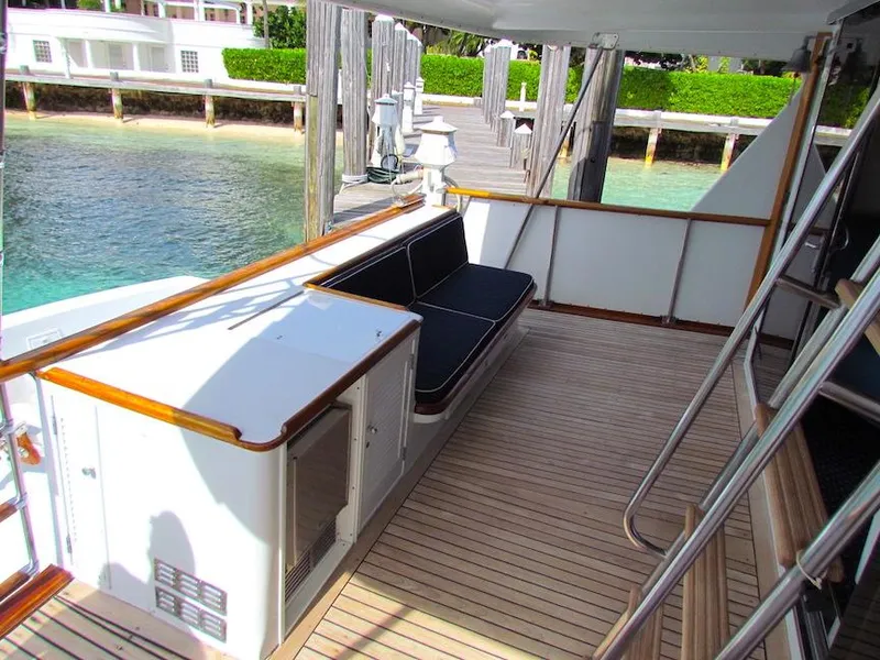 Slide: The Image of 1972 Hargrave 67 Motor Yacht deck with seating, wooden flooring, and dockside view. - 9