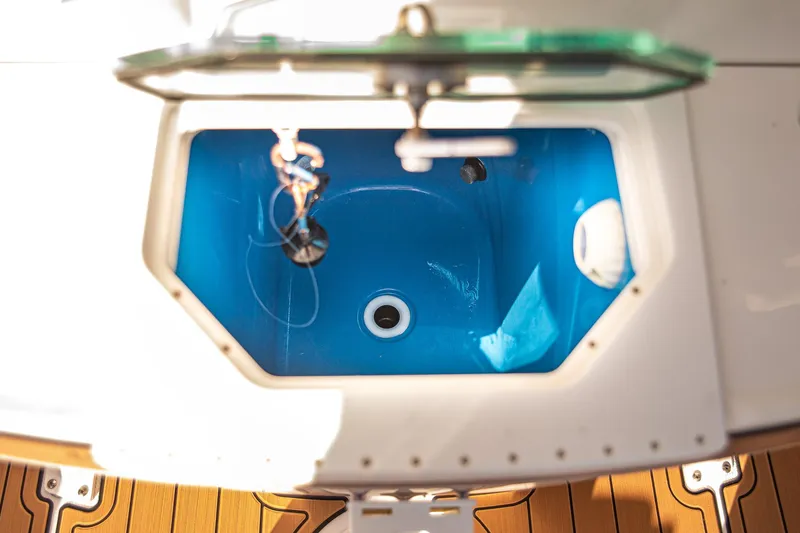 Slide: The Image of Livewell on 2017 Everglades 253 Center Console boat, featuring blue interior and wooden deck. - 49