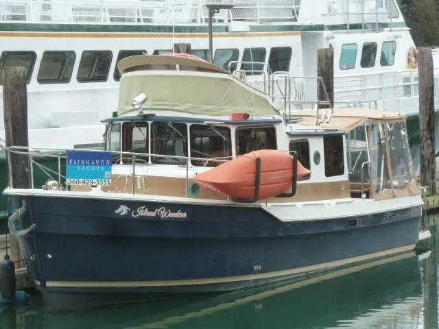 Slide: The Image of 2013 Ranger Tugs R-31 boat docked, featuring a blue hull and orange lifeboat. - 1
