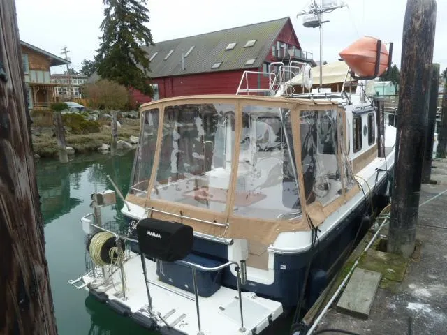 Slide: The Image of 2013 Ranger Tugs R-31 docked, featuring a covered deck and scenic waterfront setting. - 3