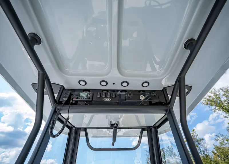 Slide: The Image of 2025 Sea Hunt Ultra 275 SE boat console with controls and radio, under a clear sky. - 20