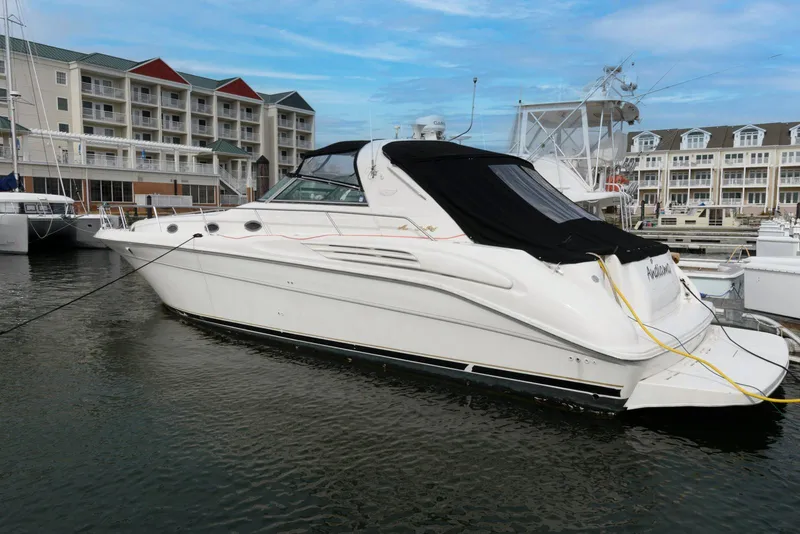 Slide: The Image of 1998 Sea Ray 450 Sundancer yacht docked at a marina with waterfront buildings. - 2